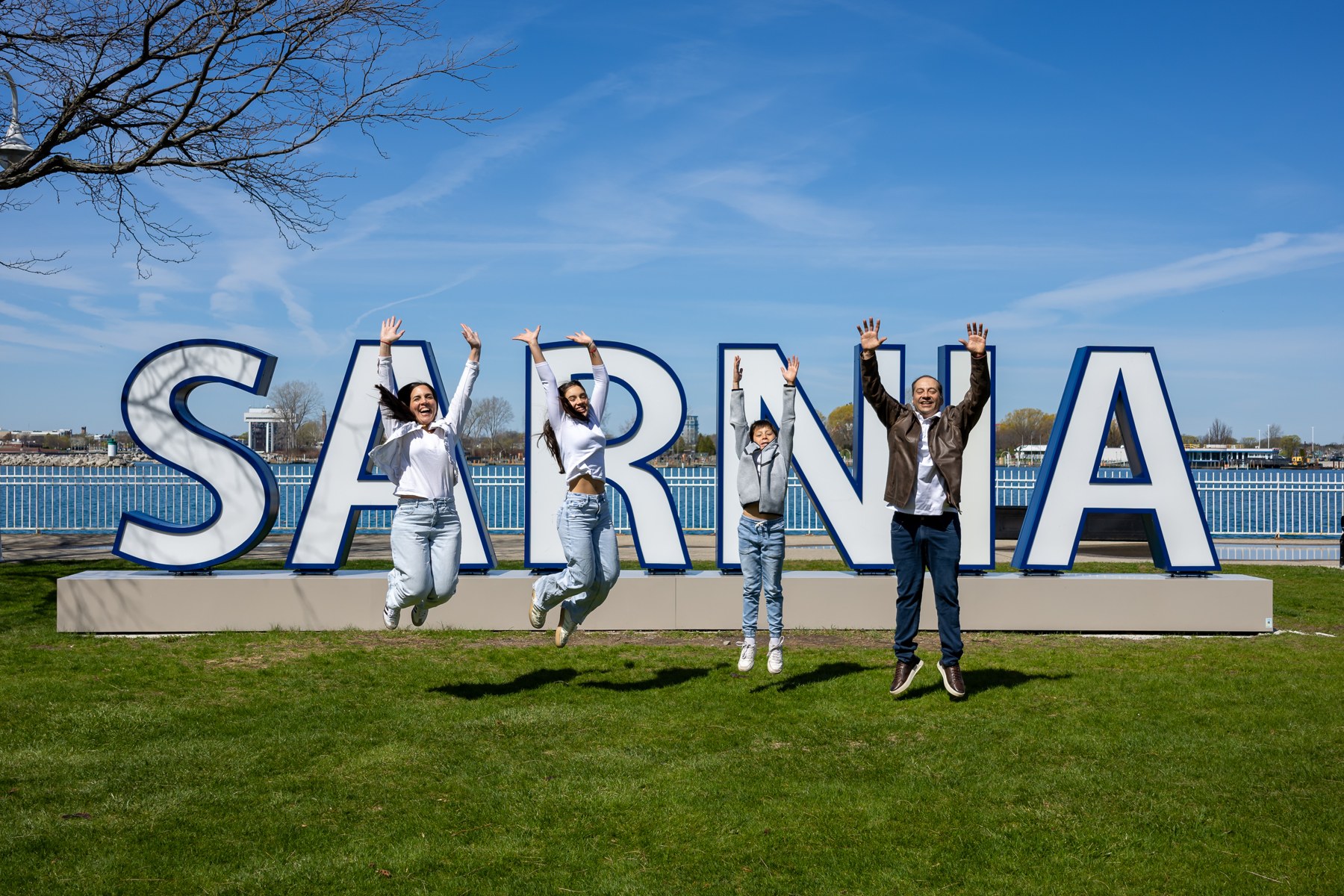Family standing across a lawn beside large waterfront lettering
