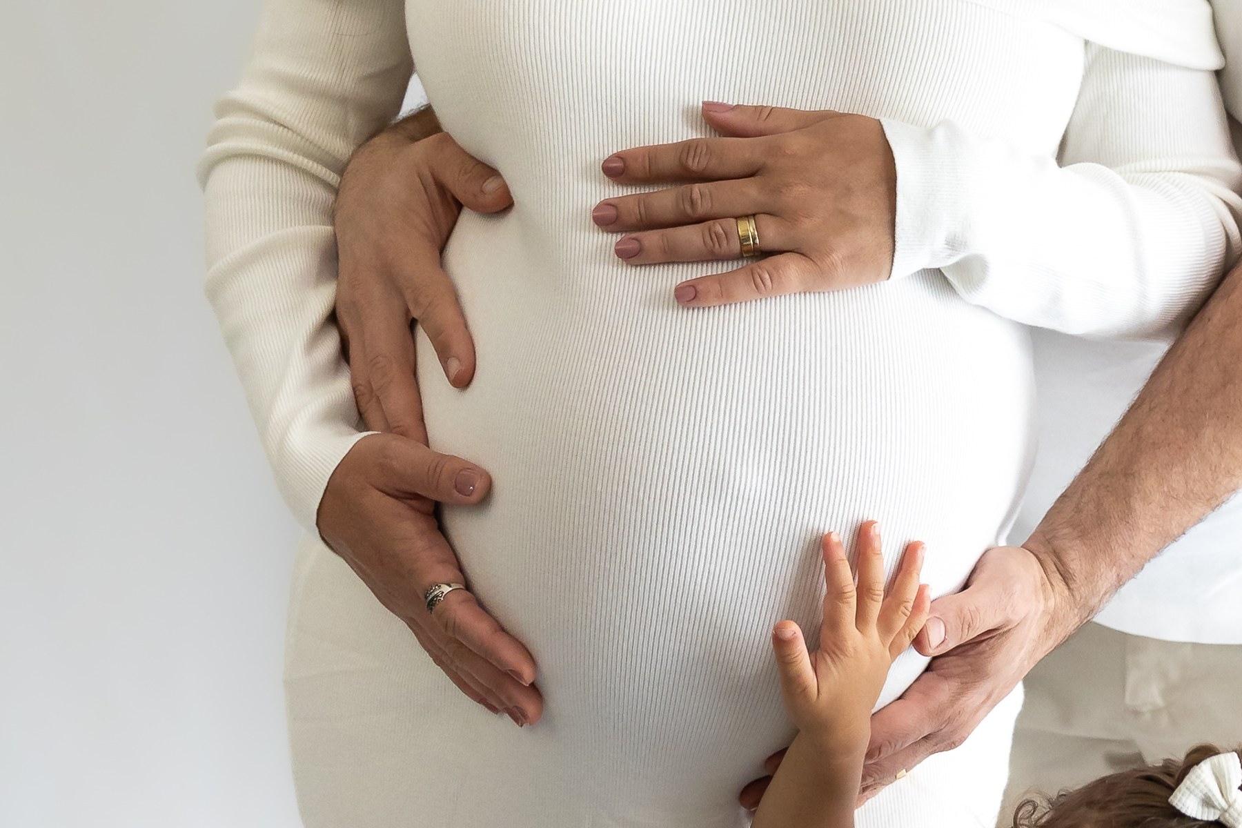 Hands resting together on an expectant mother’s bump