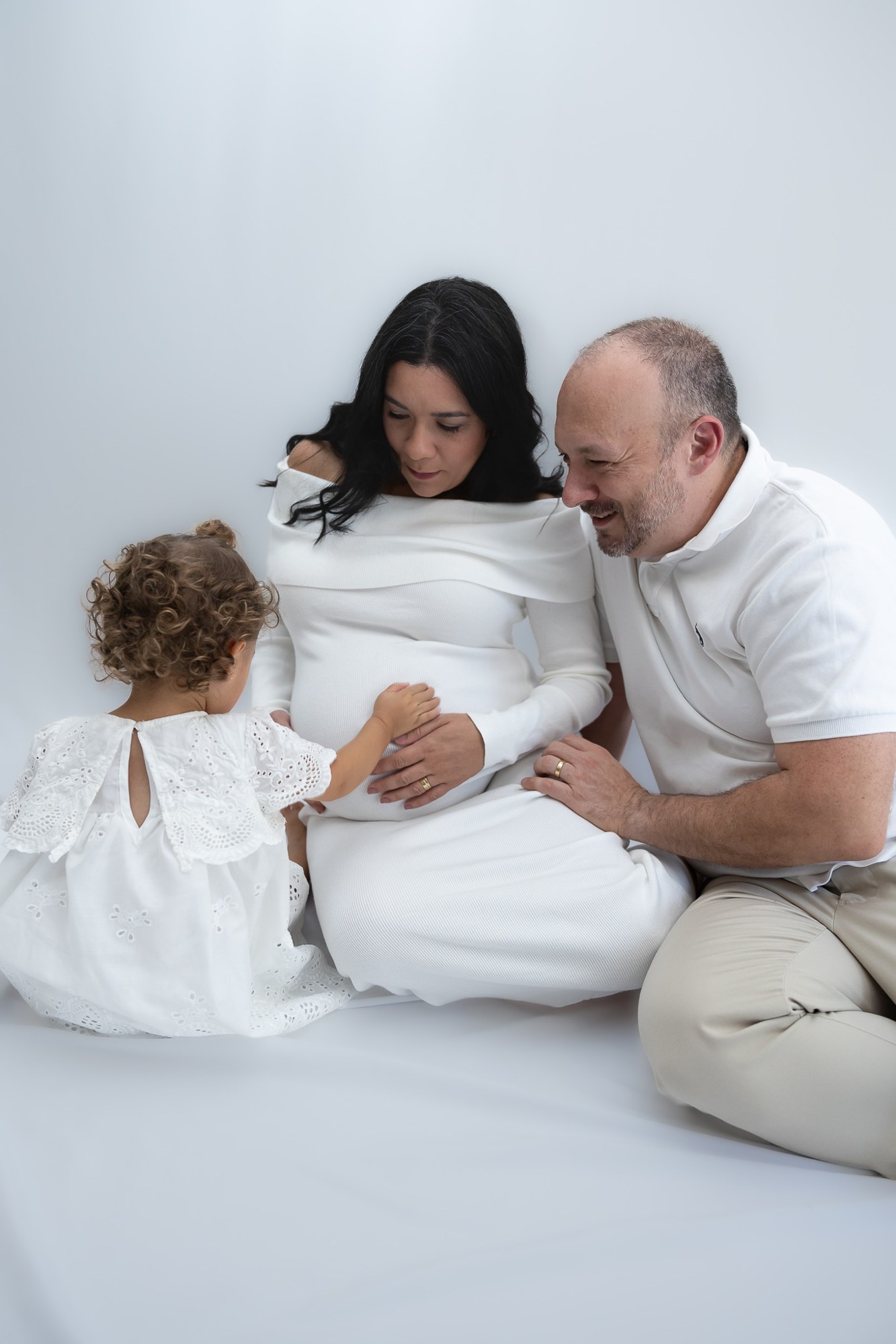 Family sitting together beside an expectant mother in a bright indoor setting