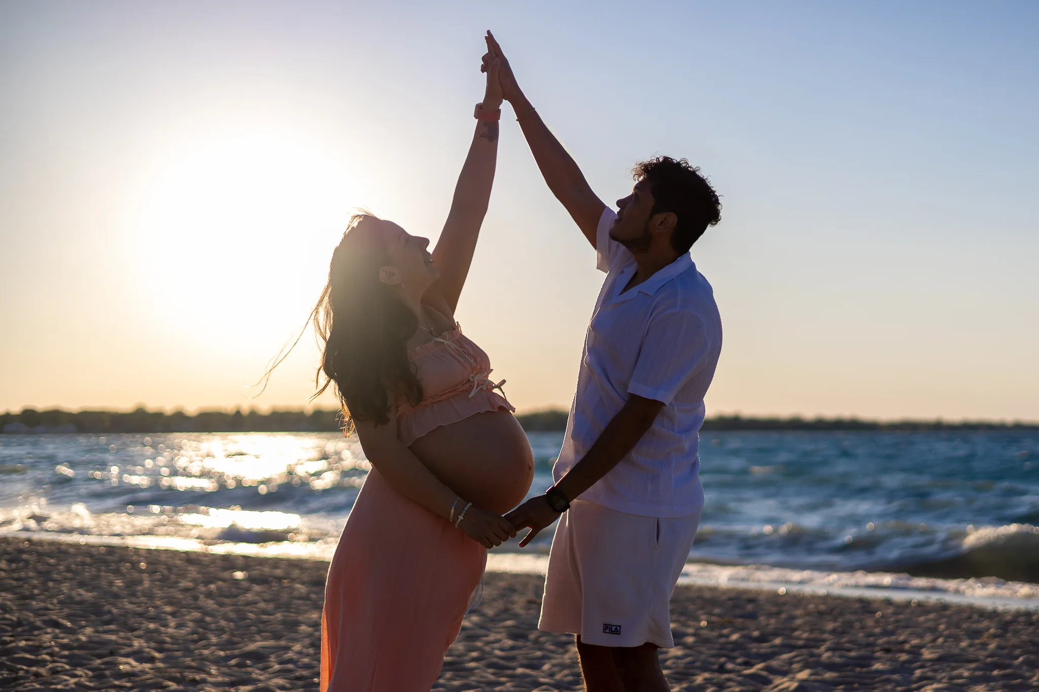 Expecting couple celebrating together on the beach