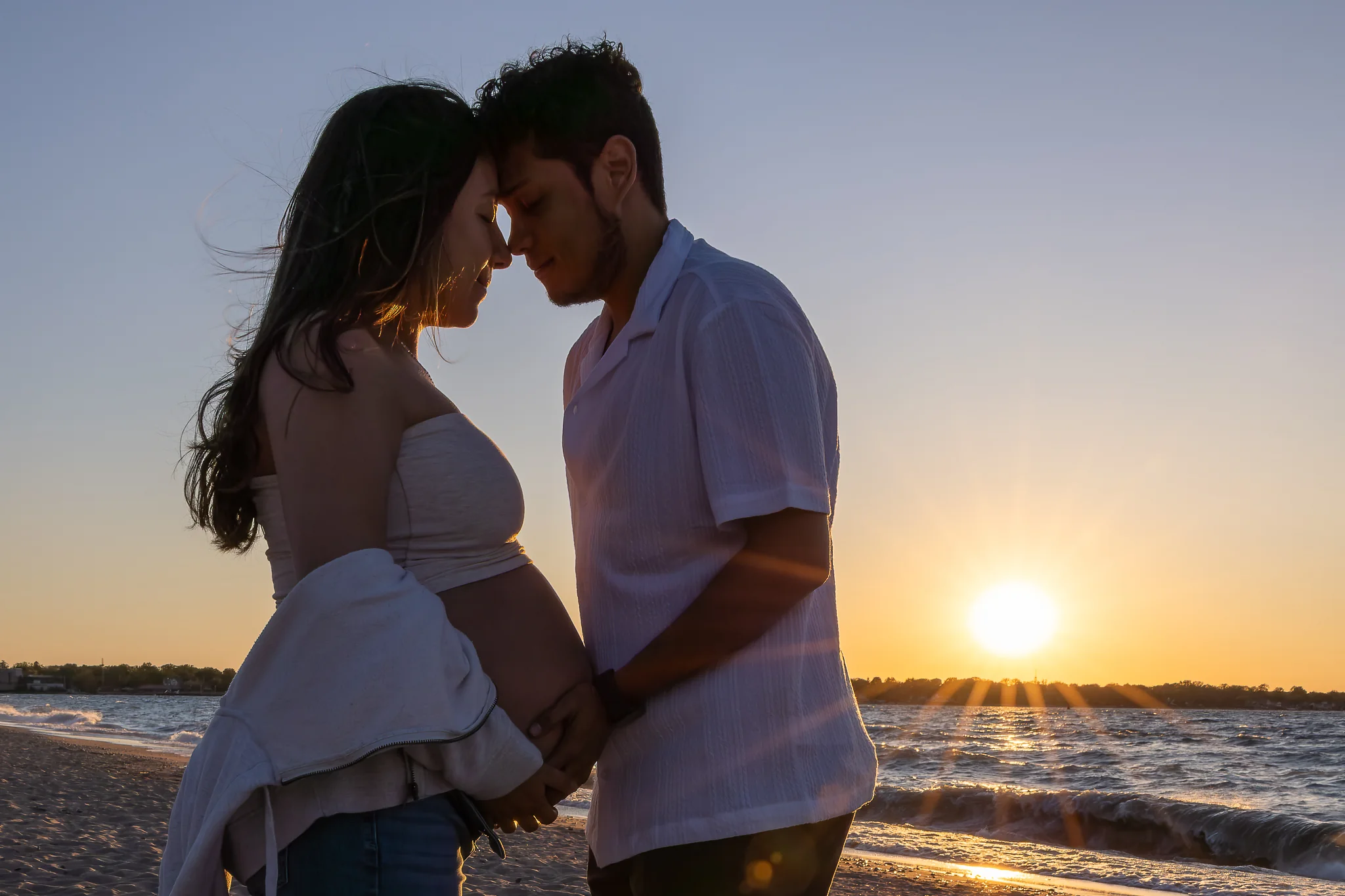 Expecting couple embracing at sunset