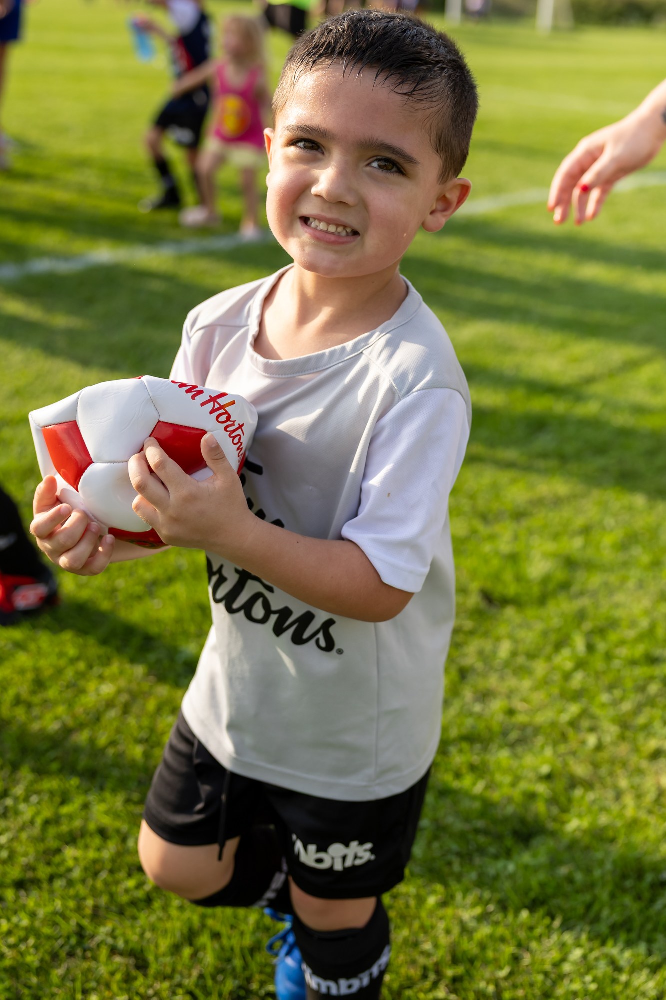 Smiling soccer player holding a ball after playing